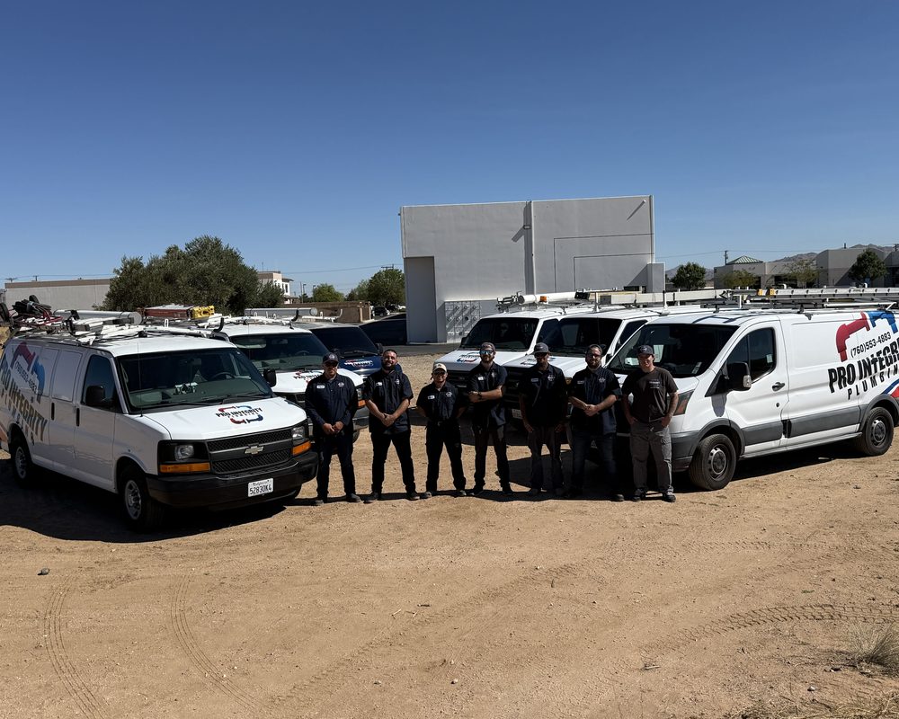 The Pro Integrity Plumbing crew standing together in front of the company's branded service vans