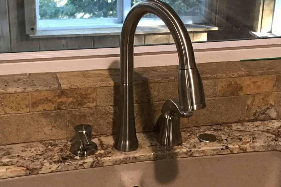 New brushed nickel pull-down kitchen faucet installed on a granite countertop in front of a window
