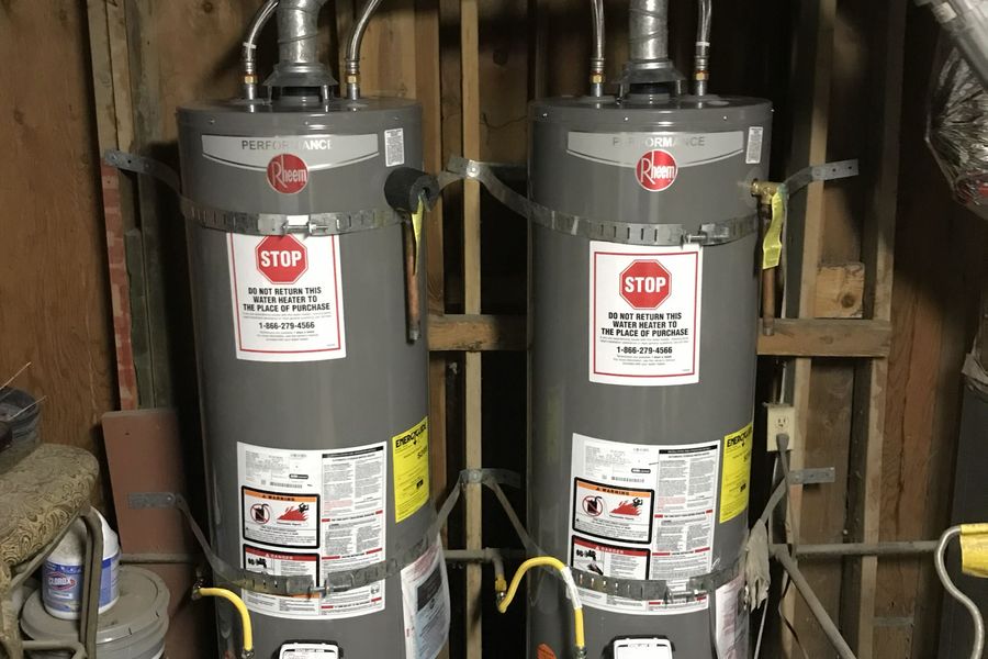 Two new Rheem water heaters installed side by side with seismic straps, flex connectors and shared venting
